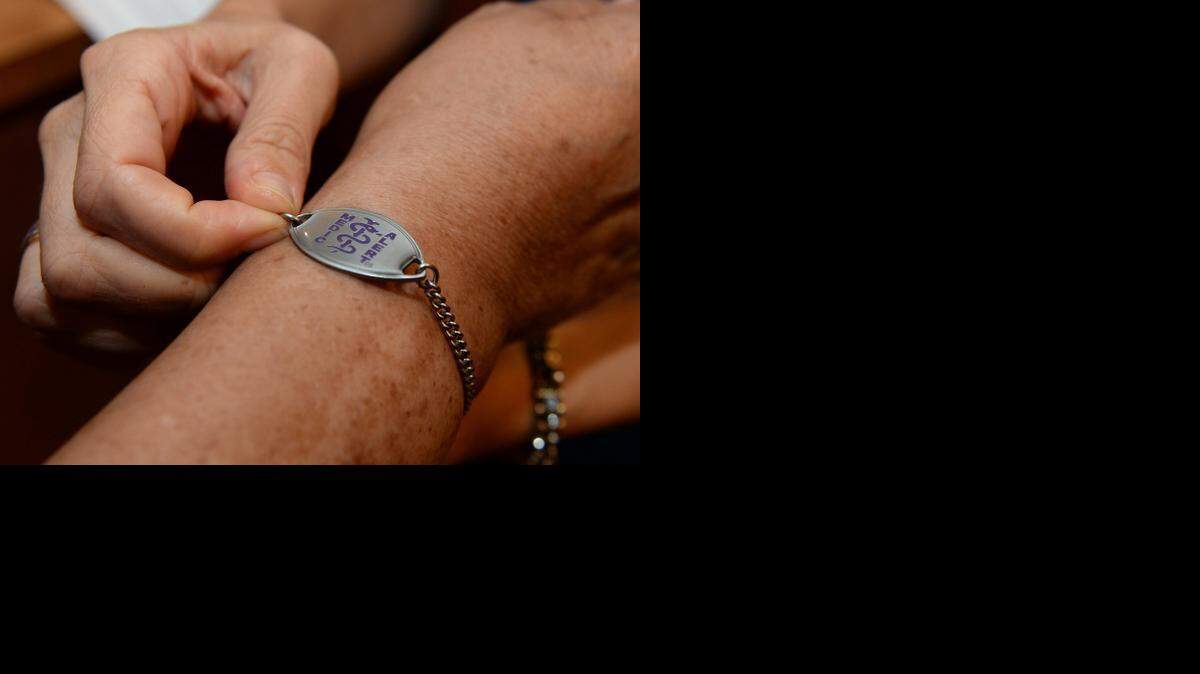 An Alzheimer’s Association worker places medic alert bracelet on a patient’s arm in Dunwoody, Georgia, September 17, 2013. 
