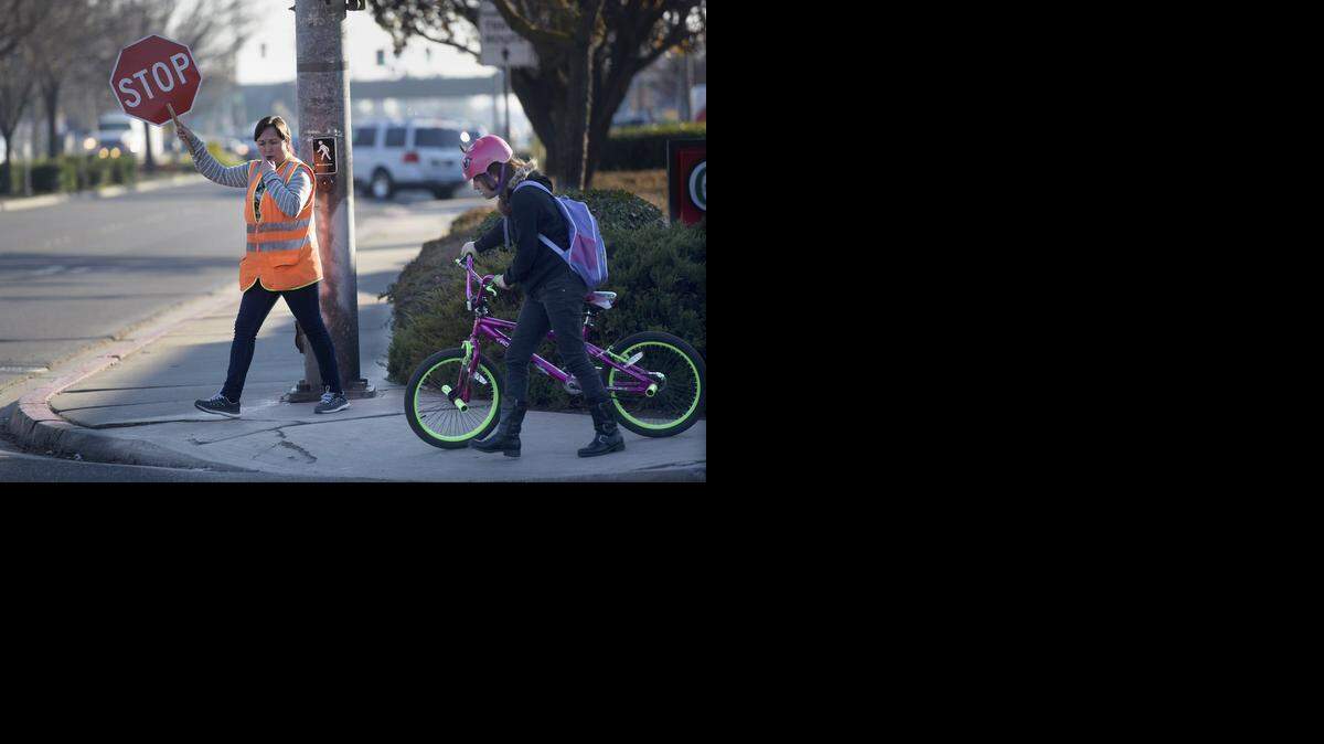 
Crossing guard Consuelo Silveira assists a bicyclist in getting across busy Lander Avenue on Monday.

