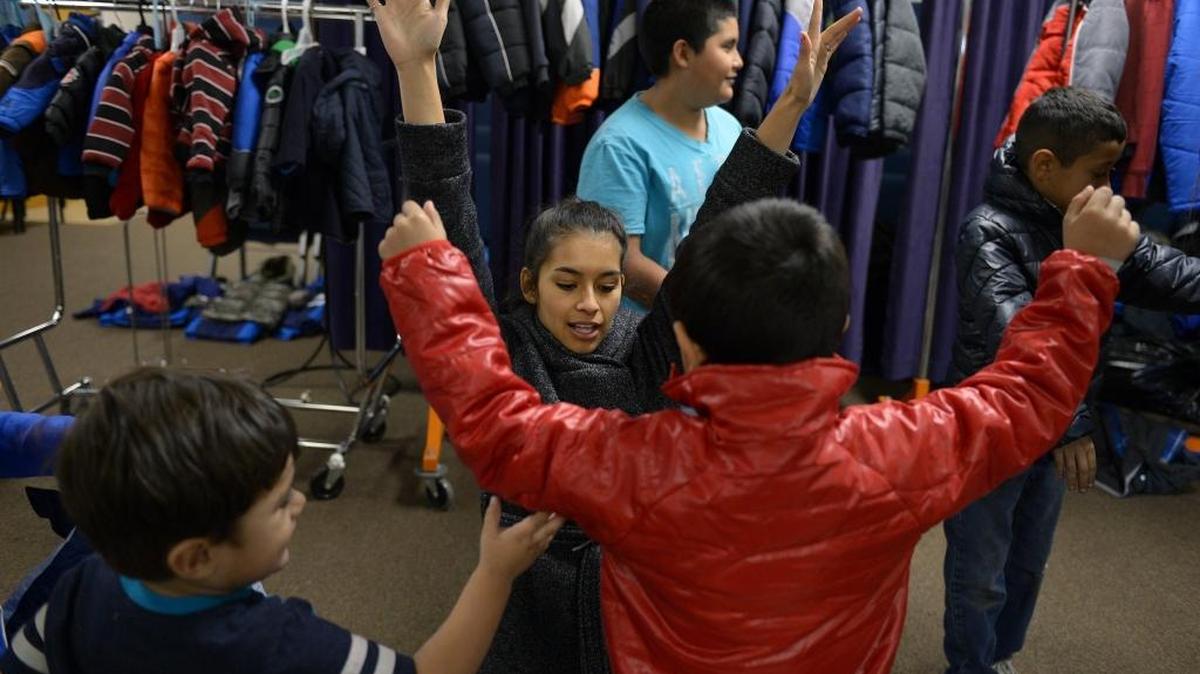 Volunteer Cameron Martinez, center, helps Cesar Avila, 6, try on a coat as his brother Edgar, 2, left, checks it out Wednesday afternoon at the Westside Ministries Coats 4 Kids giveaway in Turlock, Calif.