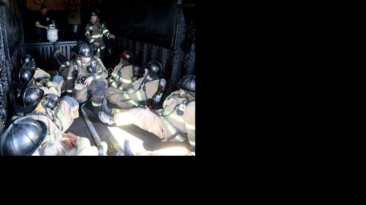 Media members and other guests are briefed by firefighters before receiving training in dealing with burn containers on Friday. The exercise simulated a flashpoint.
