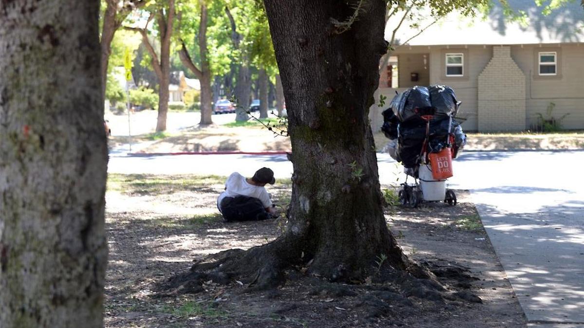 A man spends time at Enslen Park in Modesto with his belongings nearby last fall.