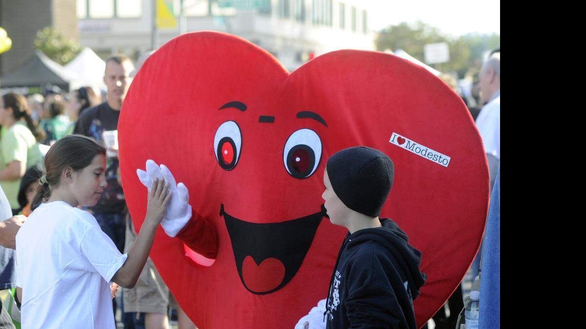 
The Love Modesto mascot high-fives Gabriella Vasquez during Love Modesto on Saturday.
