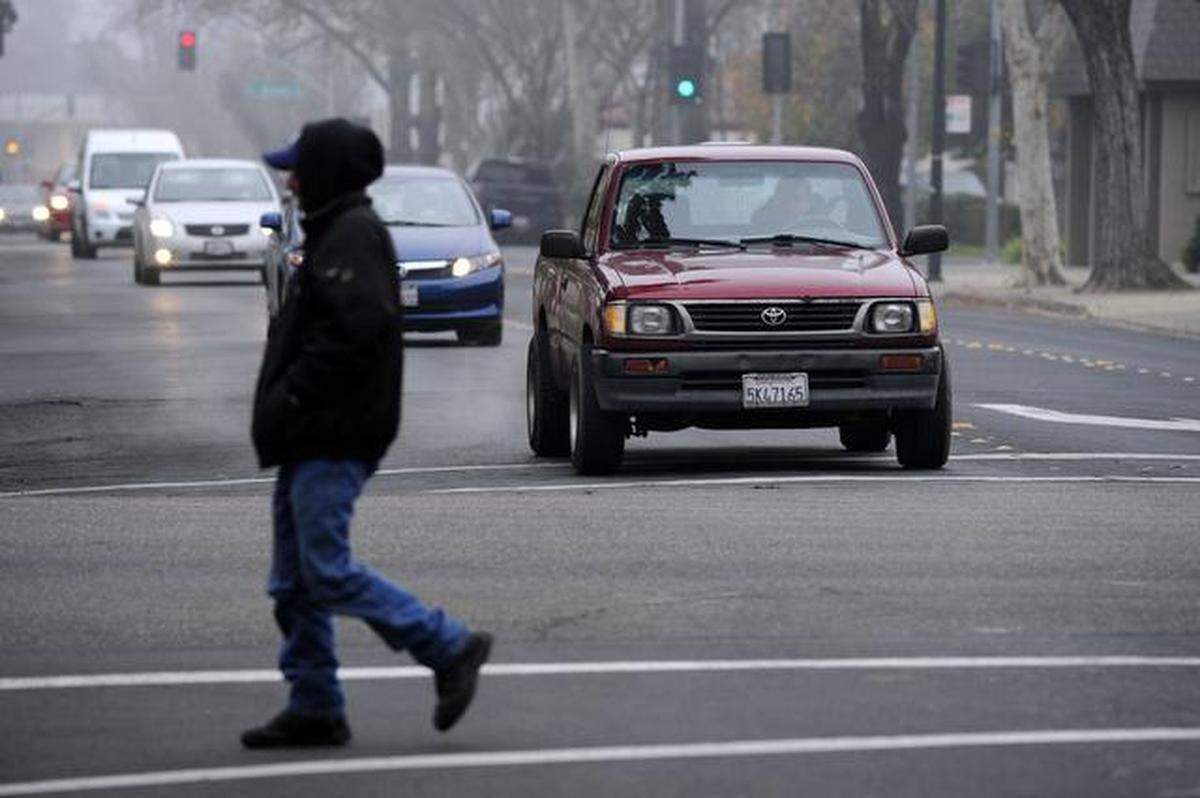 A pedestrian crosses J Street at 12th in downtown Modesto on Thursday afternoon in foggy weather.