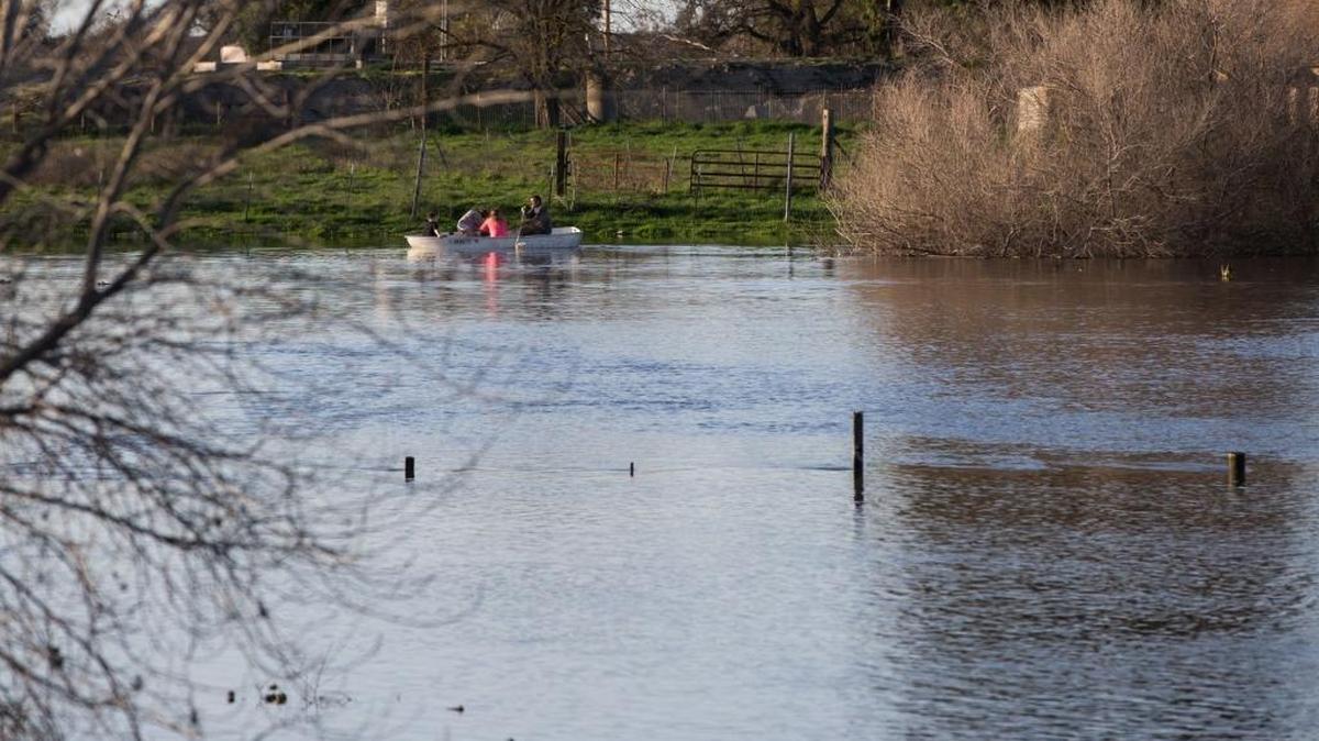 A group of people ride in a rowboat along West Main Street east of Patterson as the San Joaquin River starts to overflow its bank in the Stanislaus County area Sunday.