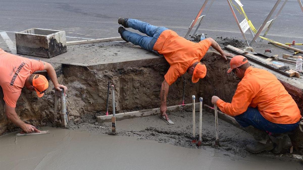 
From left, Joe McDonald, Tyler Tribble and Clayton James with the city of Modesto’s street division finish concrete Friday morning for the base of new planters going in on Tenth Street between I and J streets.
