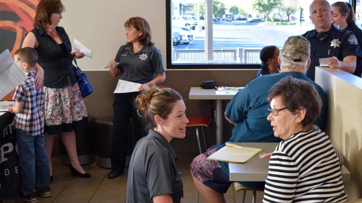 Supervisor Kaci Avrett, foreground, and crime prevention officer Rosie Garcia, background, talk with residents during the Coffee With a Cop gathering Tuesday morning at the McDonald’s restaurant at Tully Road and Standiford Avenue in Modesto.