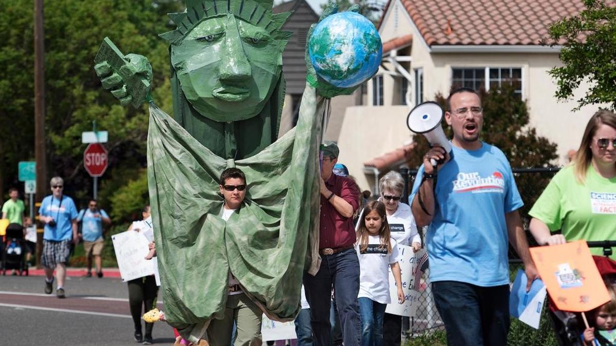 Marchers, including Michelle Park with a lady liberty costume, participate in the local March for Science during Earth Day in Modesto, Calif., on Saturday, April 22, 2017.