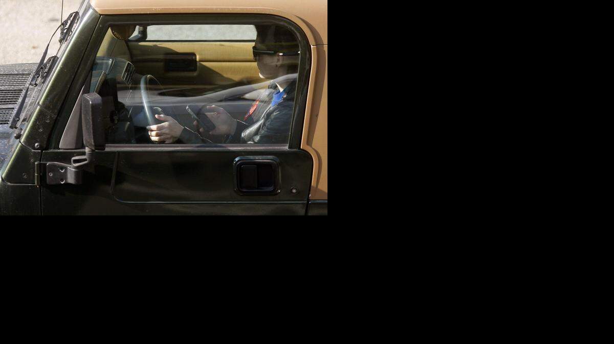 
A young driver uses an iPhone. A new study sponsored by AAA shows distracted driving is involved in nearly 60 percent of teen crashes.
