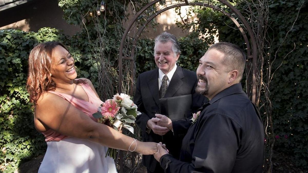 Ericka Umanzor and Jorge Galvan, right, share a laugh with officiant Johnny Matthews during a Valentine’s Day wedding ceremony at Janet’s Flowers and Wedding Chapel in Modesto on Sunday, Feb. 14, 2016.