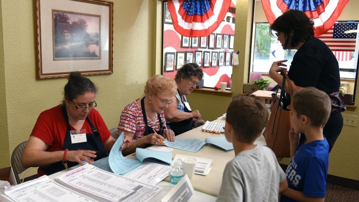 Poll workers at Standiford Place in Modesto, Calif., check in voter Stephanie Bowers with her 6-year-old twins Joshua and Jason, right. The poll workers, from left, are Theresa Villarreal, Marilyn Coats and Delores Aguilar.