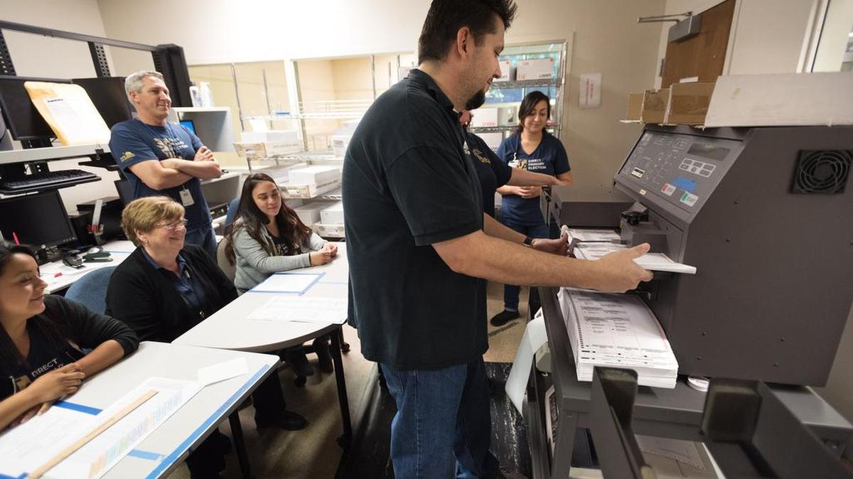 Senior Systems Engineer Aaron Rosa feeds ballots into the tabulation machine at the Stanislaus County Registrar of Voters office in Modesto, Calif., Friday, June 6, 2018.