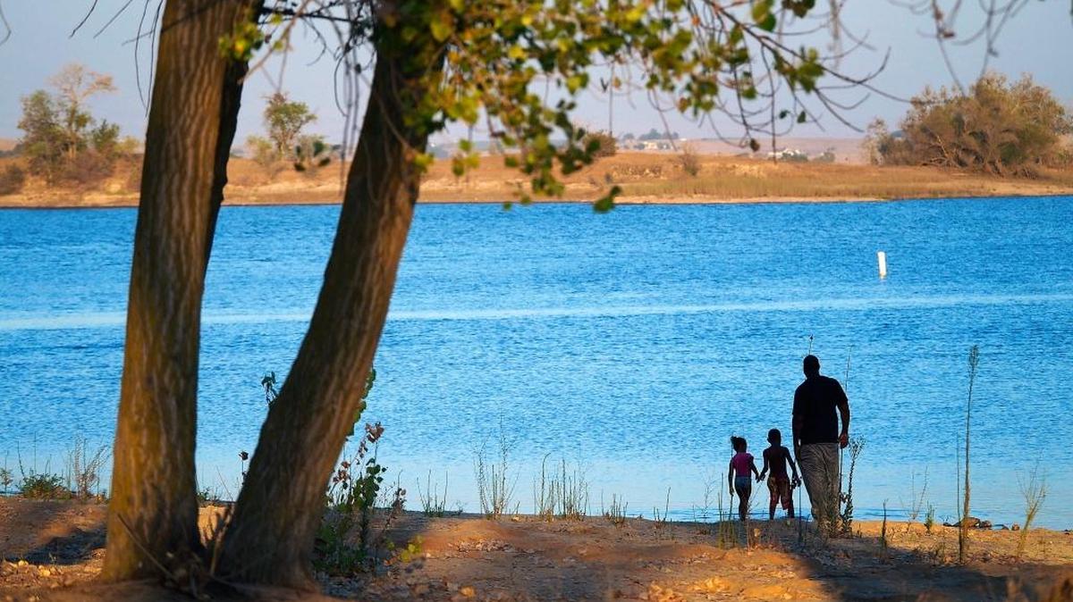 Visitors take a last look at the lake under the warm glow of the late evening sun at Turlock Lake State Recreation Area.