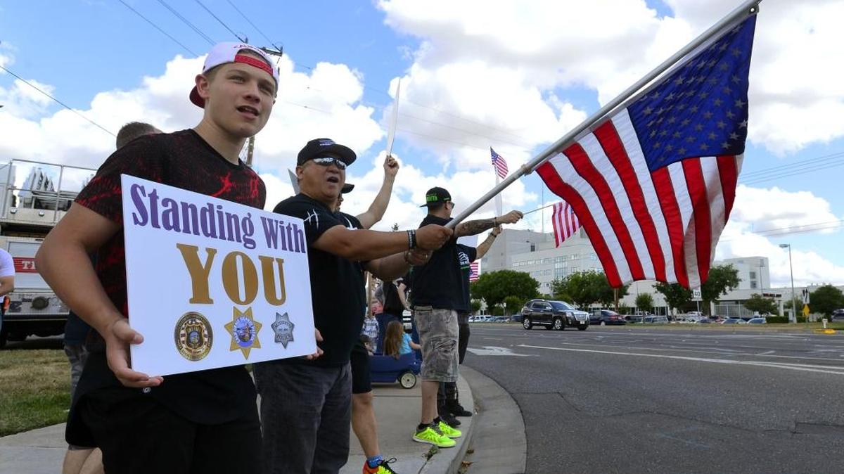Dorian Knox, left, holds a sign and Leo Castro holds an American flag at Coffee Road and Briggsmore Avenue in Modesto on Saturday, May 21, 2016, as part of the Standing With You event to show appreciation for Modesto and Stanislaus law enforcement agencies.