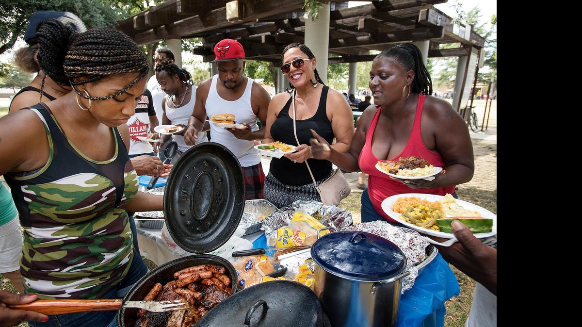 
Quatrice Williams, left, serves up hot links and chicken that mother Estelle Counts, right, cooked for more than 60 family and friends during the Juneteenth Celebration at Mellis Park in Modesto on Saturday.
