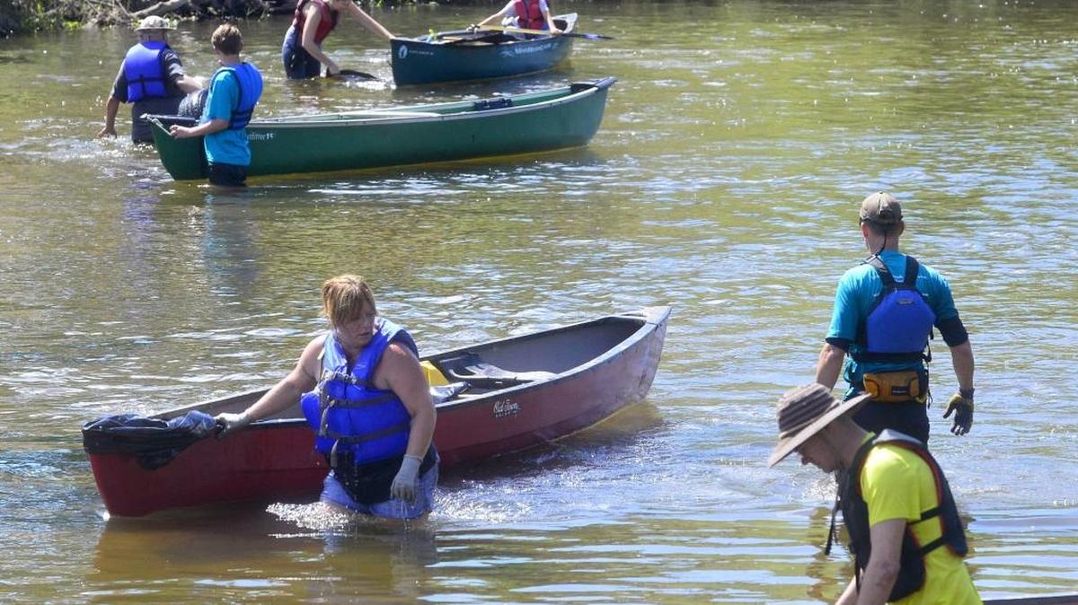 Volunteers wade through the water of the Tuolumne River to find and remove trash during the Operation 9-2-99 cleanup effort on the Tuolumne River in Modesto on Sunday, May 22, 2016.