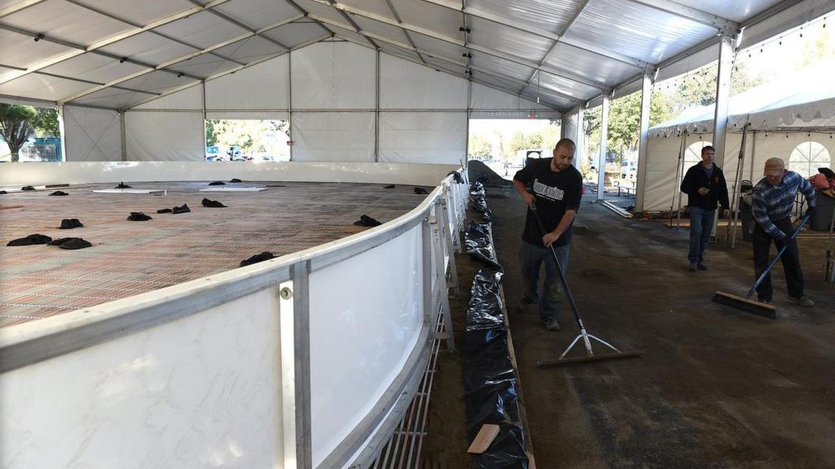 Daniel Gonzales (center right) sweeps sand on Thursday morning (11-12-15) at the new ice rink on 11th and K streets in downtown Modesto, Calif.