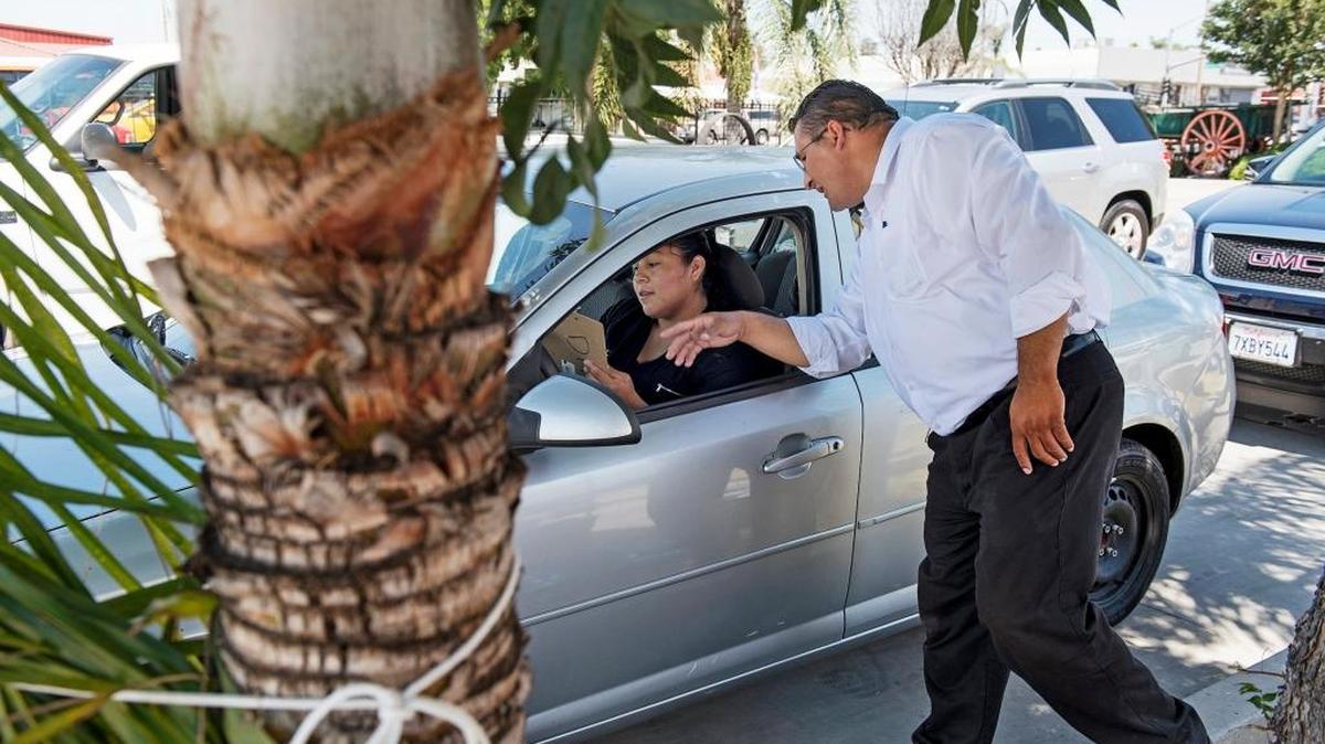 Modesto City Councilmember Tony Madrigal assists Jennifer Alva with paperwork during a Child Safety Seat Check event on Crows Landing Road in Modesto, Calif., on Saturday, June 24, 2017.