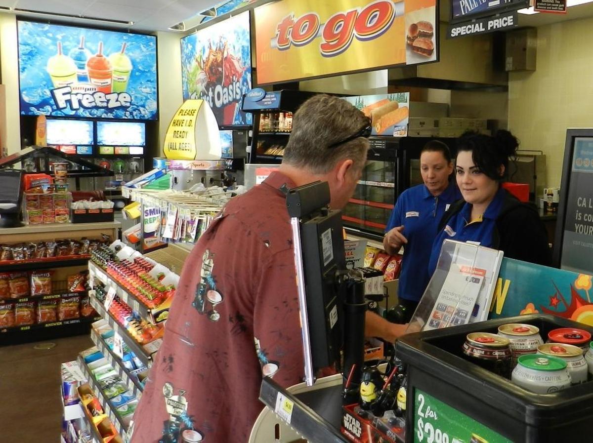 Katherine Rodriguez, left, and Juliana Shea help a customer at the Arco AM-PM mini-mart on McHenry Avenue at Rumble Road on Christmas Day afternoon.