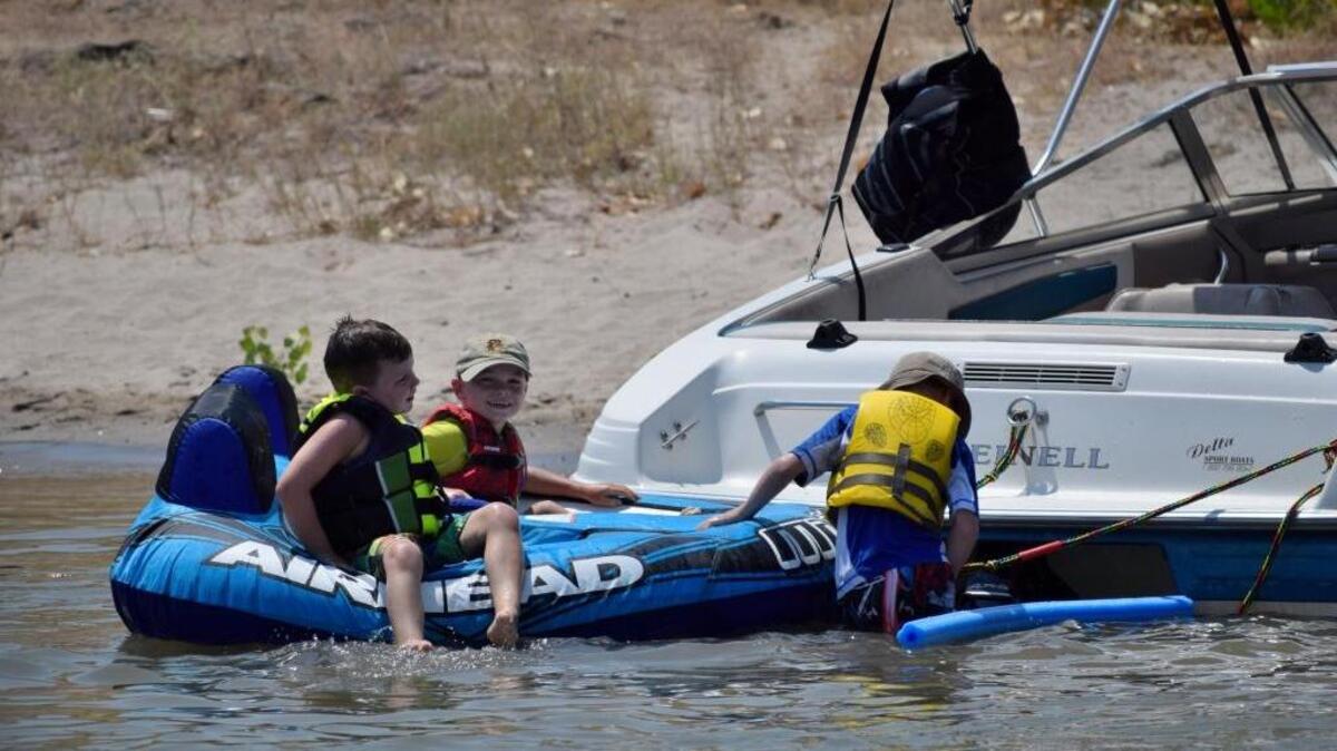 Small children wear life vests as they play on an inflatable raft tethered to a boat on the shore at Modesto Reservoir Regional Park on Sunday, July 31, 2016.