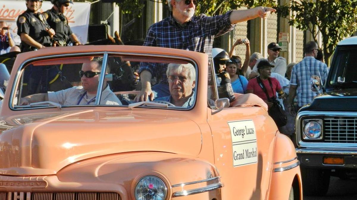 Modesto native son and iconic filmmaker George Lucas acknowledges the crowd during the 2013 American Graffiti Classic Car Parade.