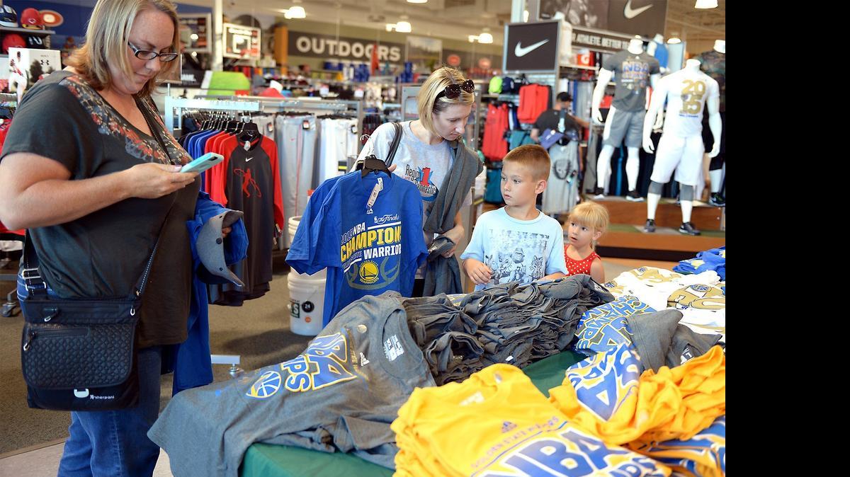 
Jamie Holt of Ripon (left) takes a photo of a Golden State Warriors shirt she was thinking of buying Wednesday at Dick’s Sporting Goods in Modesto. Holt was shopping with her 8-year-old son, Jacob, and 4-year-old daughter, Paige.

