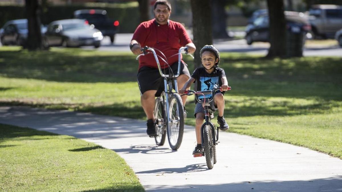 Nick Figueroa and his nephew Jasyiah Roberts ride their bikes in Roosevelt Park in Modesto, Calif., on Friday, September 14, 2017.