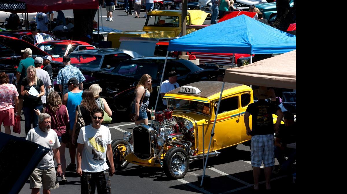 
 People walk by a yellow taxi 1931 Ford owned by Tim and Gail Dalton of Riverbank at the Graffiti Classic car show held at McHenry Village in 2012.
