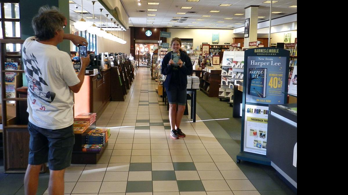 
Robert Benz photographs his daughter, Shelby Benz, after she is the first person to pick up her copy of Harper Lee’s novel “Go Set a Watchman” at Modesto’s Barnes & Noble bookstore on Tuesday. 
