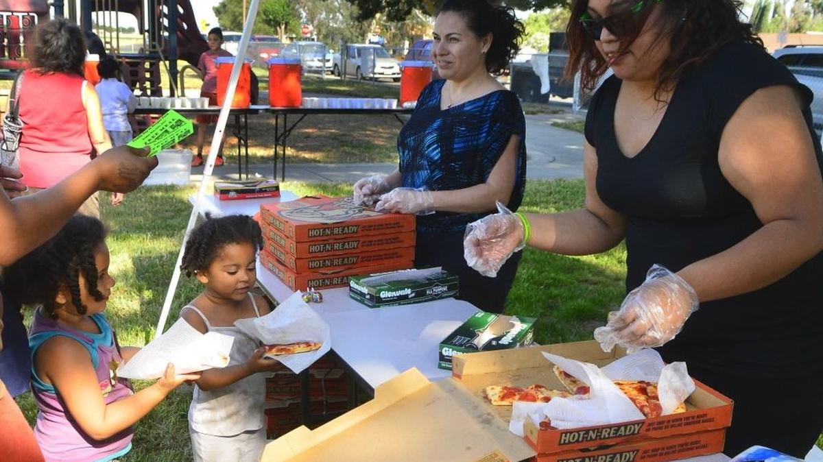 Vanity Lucas, left, receives pizza from Stephanie Hoyos, right, during Family Day at Oregon Park in Modesto, Calif., on Friday, May 13, 2016.