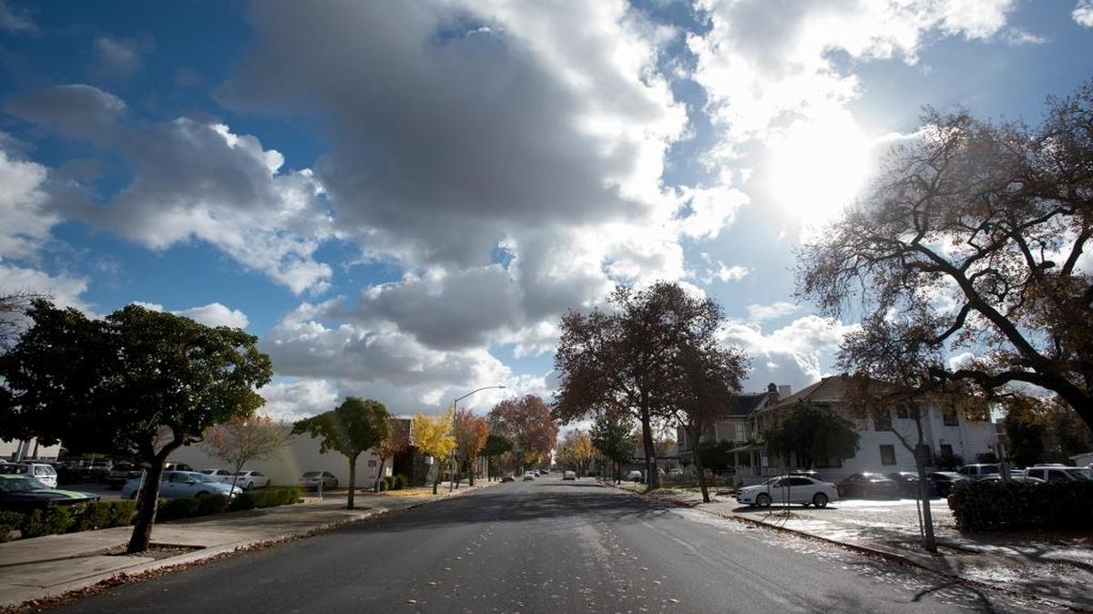 The sun breaks through the partly cloudy skies above 14th Street in Modesto, Calif., on Thursday, Dec. 11, 2015.