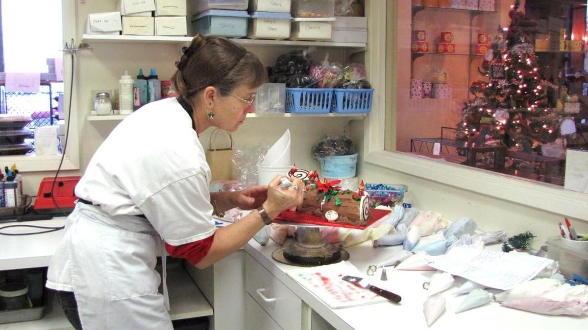 Naomi Erg adds festive touches to a yule log at Old Tyme Pastries in Turlock on Christmas Eve.