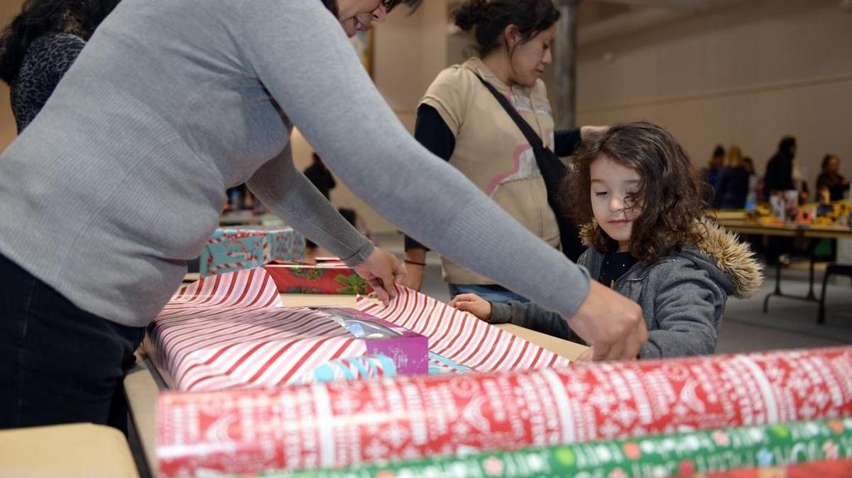 Katie Burch, 4, helps volunteer Scherlis Khoshaba wrap her Christmas present Thursday morning, Dec. 17, 2015, during the St. Vincent de Paul ministry’s Christmas basket and toy distribution at St. Joseph’s Catholic Church in Modesto.