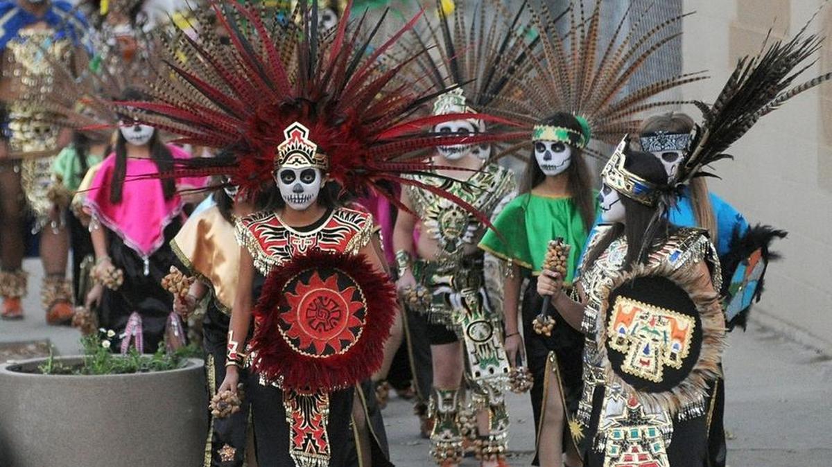 Members of the traditional Aztec dancers Ballet Folklorico Anahuac lead a procession of Dia de los Muertos participants to Modesto Centre Plaza along K Street on Nov. 1, 2013.
