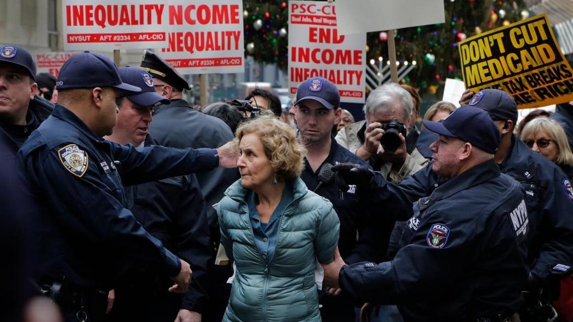 Police handcuff a woman protesting the proposed tax overhaul in front of the New York Stock Exchange on Tuesday. Many believe the real aim of the overhaul is to diminish or privatize programs like Medicare and Social Security.