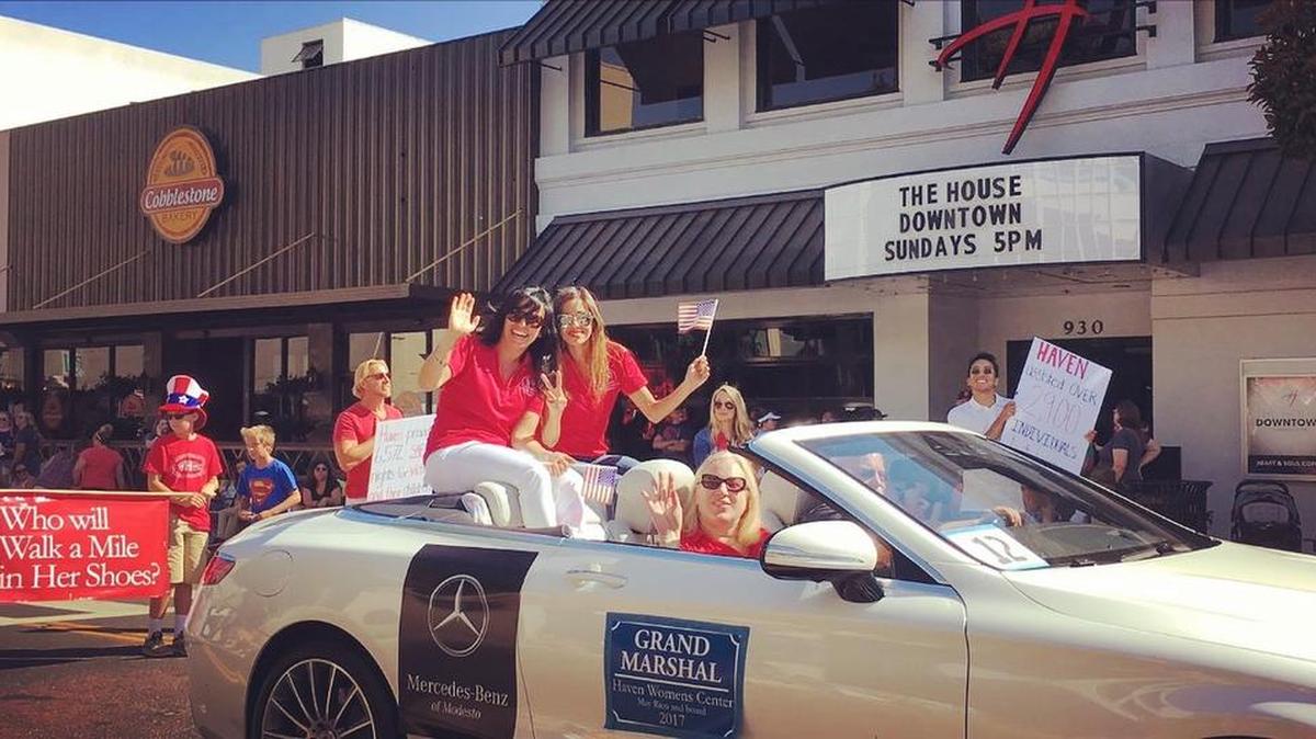 Haven board members Natalia Diryawush, foreground, and Jen Dittman ride in the back of a Mercedes during Modesto’s Fourth of July parade, with executive director May Rico in the front.