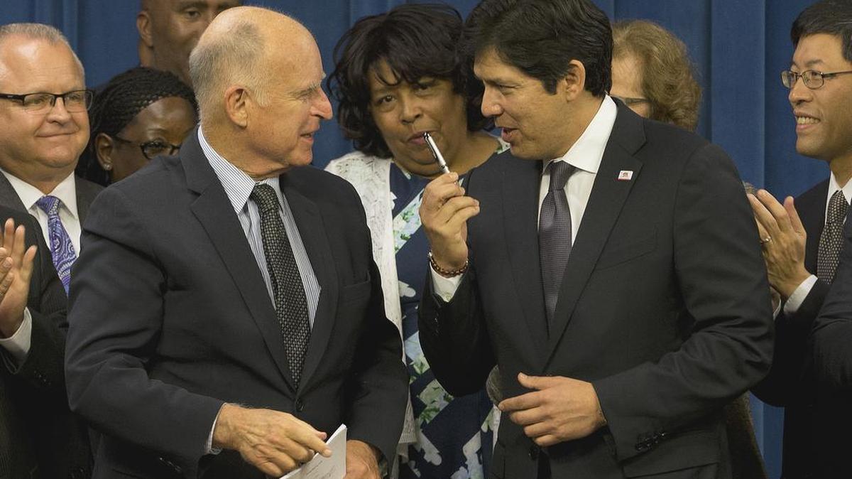 Senate President Pro Tem Kevin de León, D-Los Angeles, right, thanks Gov. Jerry Brown after he gave de León the pen used to sign legislation to automatically enroll millions of private-sector workers in retirement saving accounts in September. The law is now under attack by congressional Republicans.