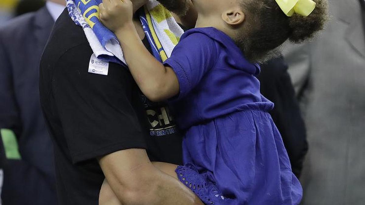 Golden State Warriors guard Stephen Curry kisses his daughter Riley as the team celebrates its championship victory over the Cleveland Cavaliers.
