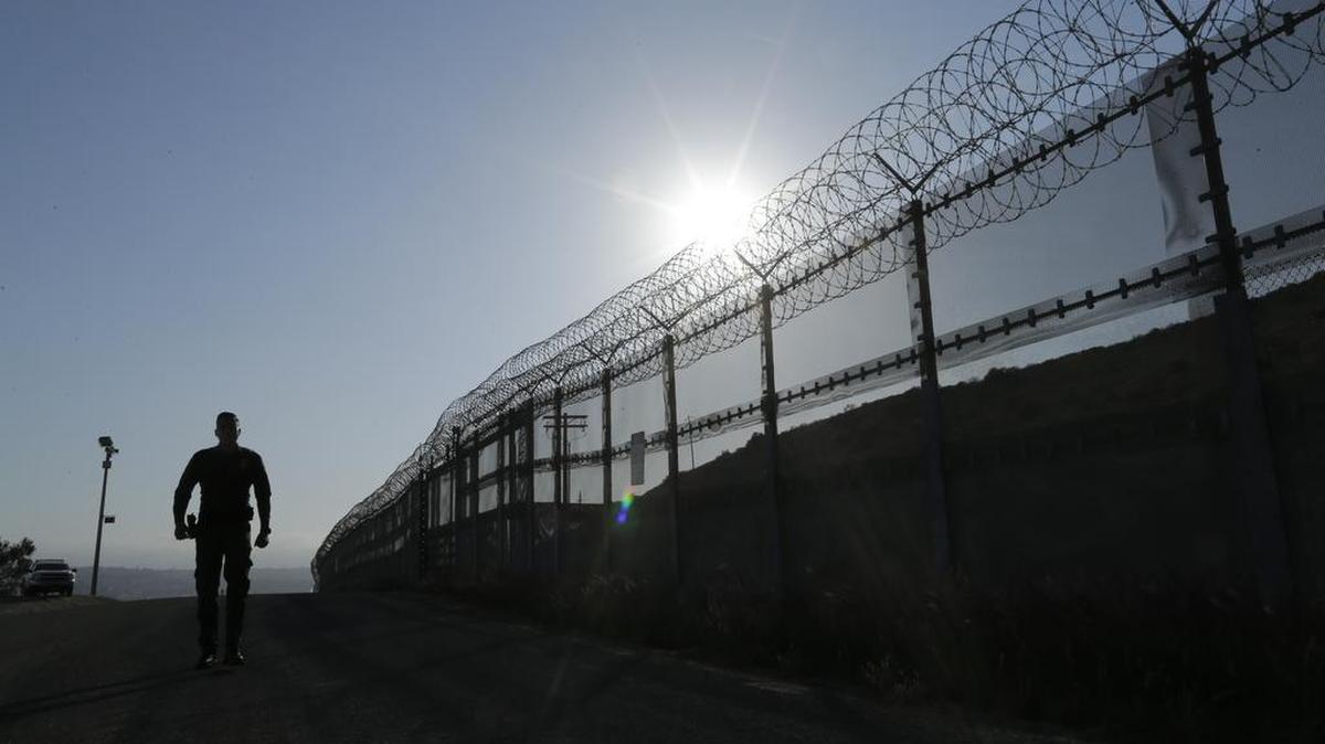 A Border Patrol agent walks along the fence separating the United States from Mexico in San Diego, Calif. The Department of Homeland Security may exempt many veterans and law enforcement officers from a requirement that new hires take a lie-detector test.
