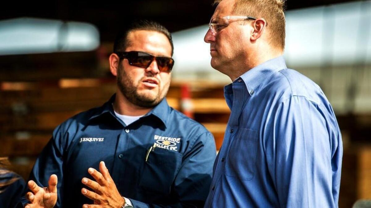 Rep. Jeff Denham, right, speaks with Westside Pallet Inc. production supervisor Juan Esquivez while touring the facility in Newman, Calif., in 2015.