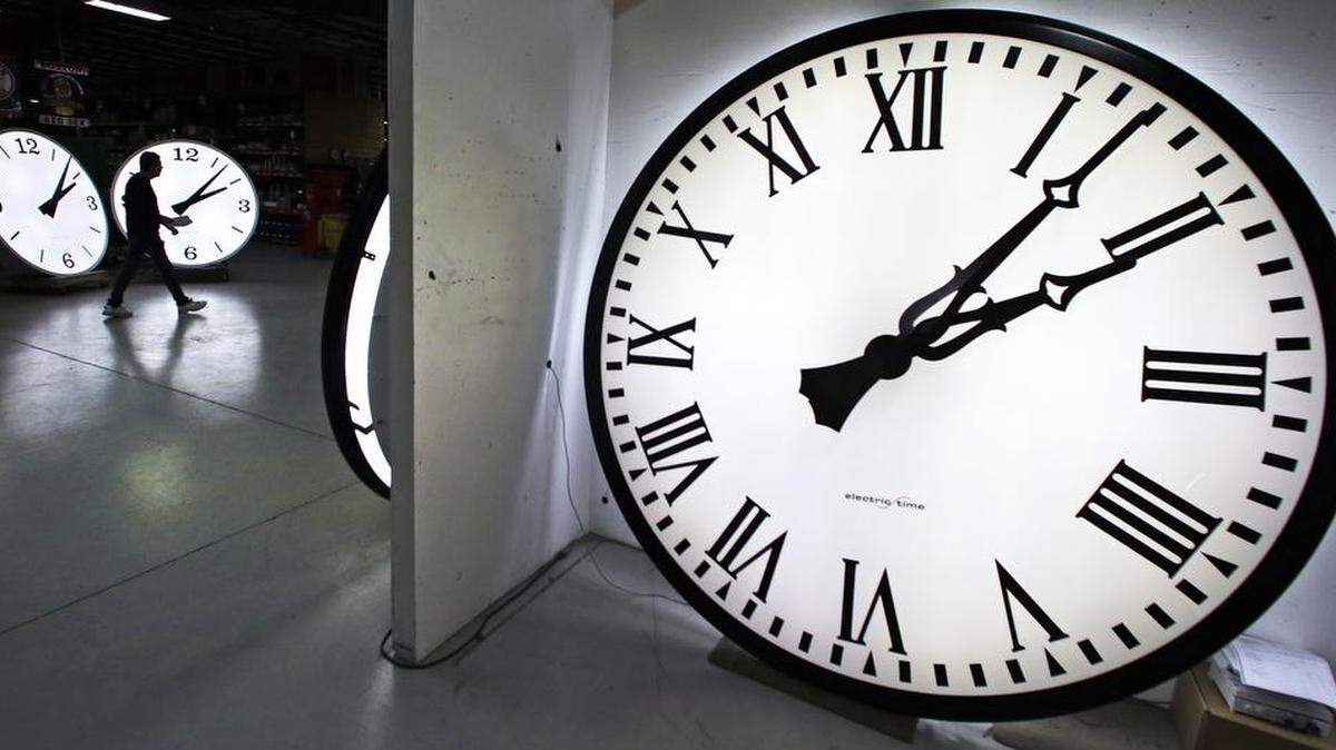 A worker walks past clocks being tested prior to shipping at the Electric Time Co. in Medfield, Mass.