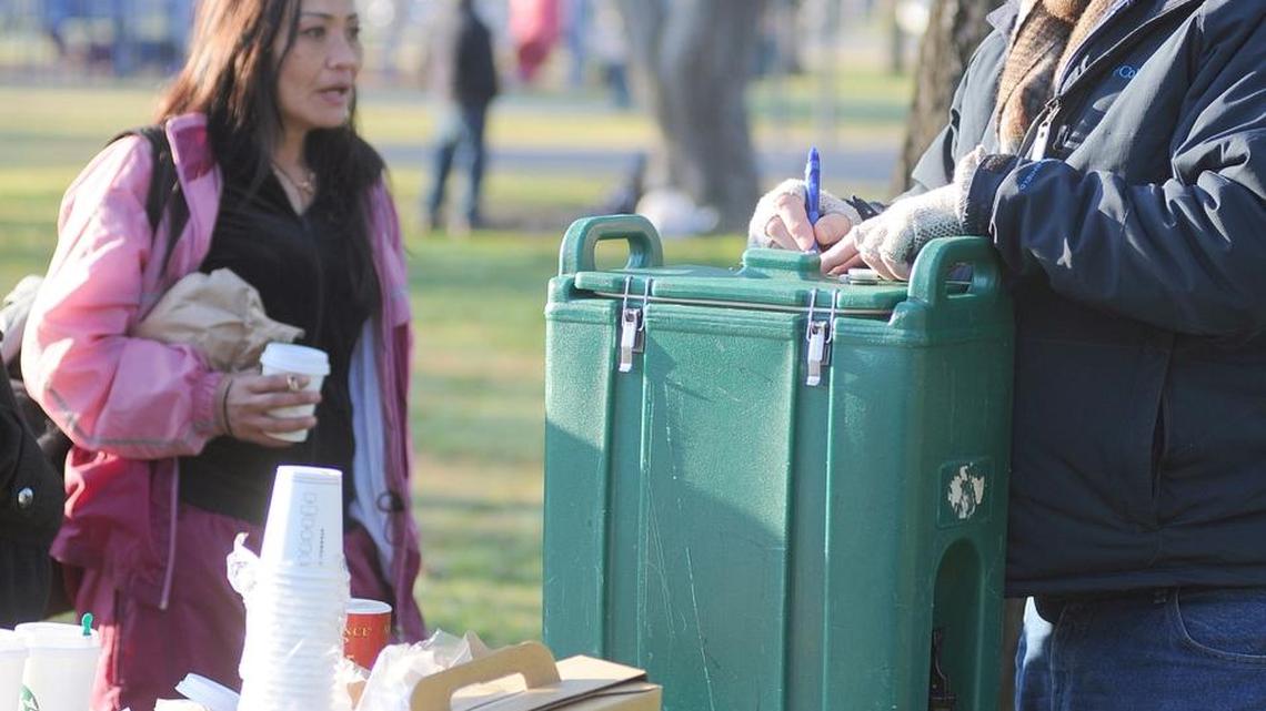 An employee of non-profit Turning Point offers a card to a homeless woman at Cesar Chavez Park in Modesto. Non-profits now provide dozens of services to the most vulnerable people living in Stanislaus, San Joaquin and Merced counties. If AB 1250 passes, the county would have to take over those services or let them lapse altogether.