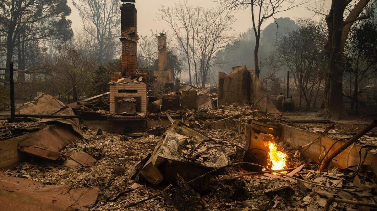 Small flames continue to burn at remnants of a house destroyed by the Camp Fire on Skyway road in Paradise.