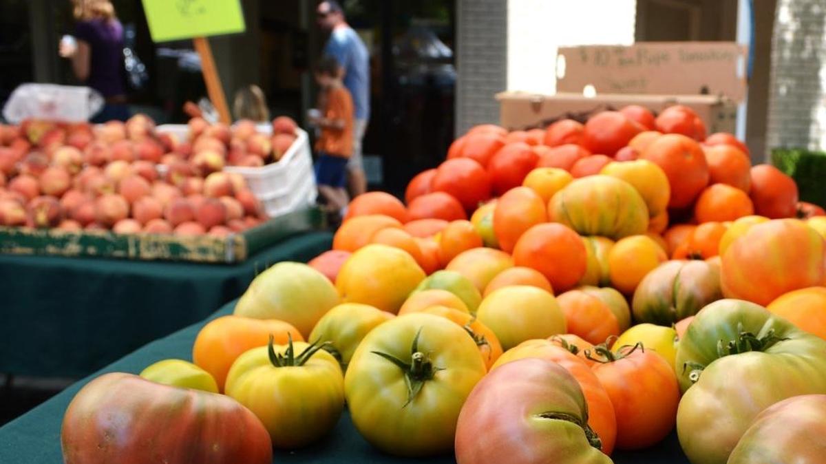 A variety of tomatoes and bins of peaches beckon to shoppers at the Turlock Farmers Market along East Main Street in August 2015.
