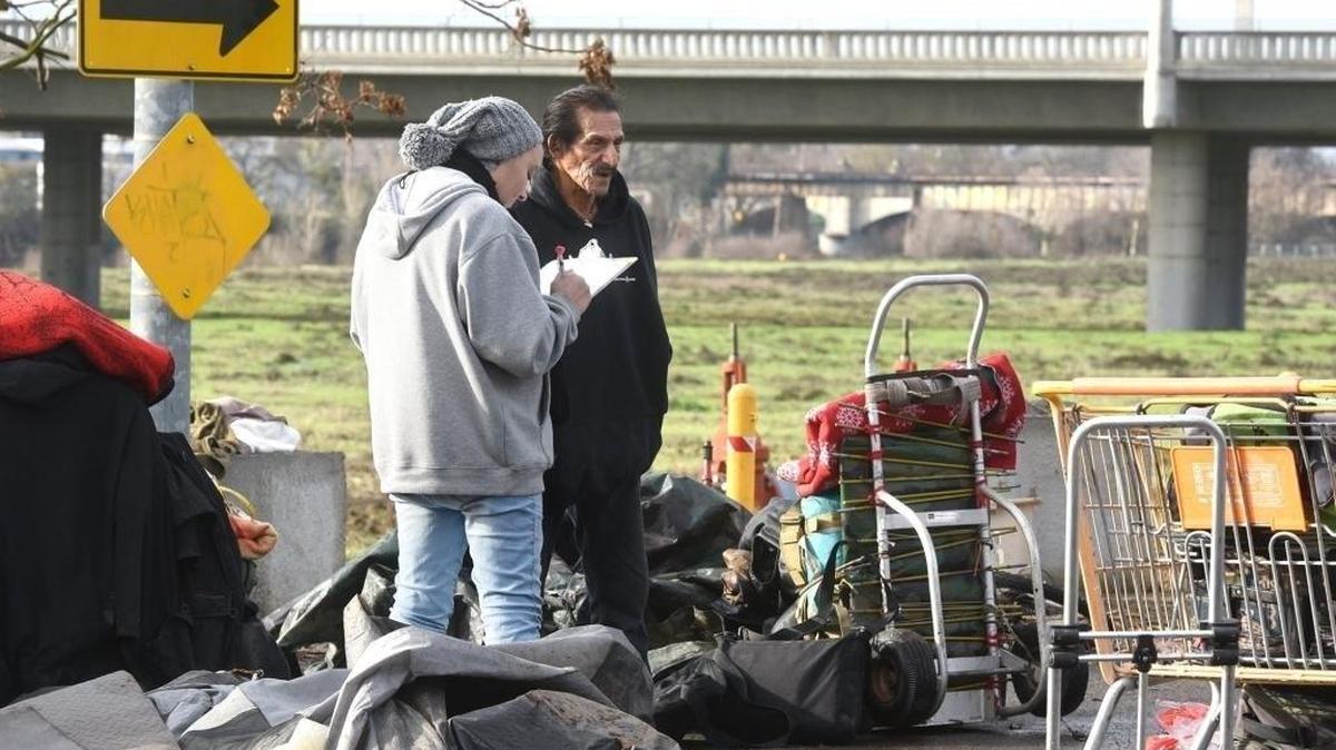 An outreach specialist takes information from a person living along the Tuolumne River in Modesto during the annual count of homeless people in January 2018.