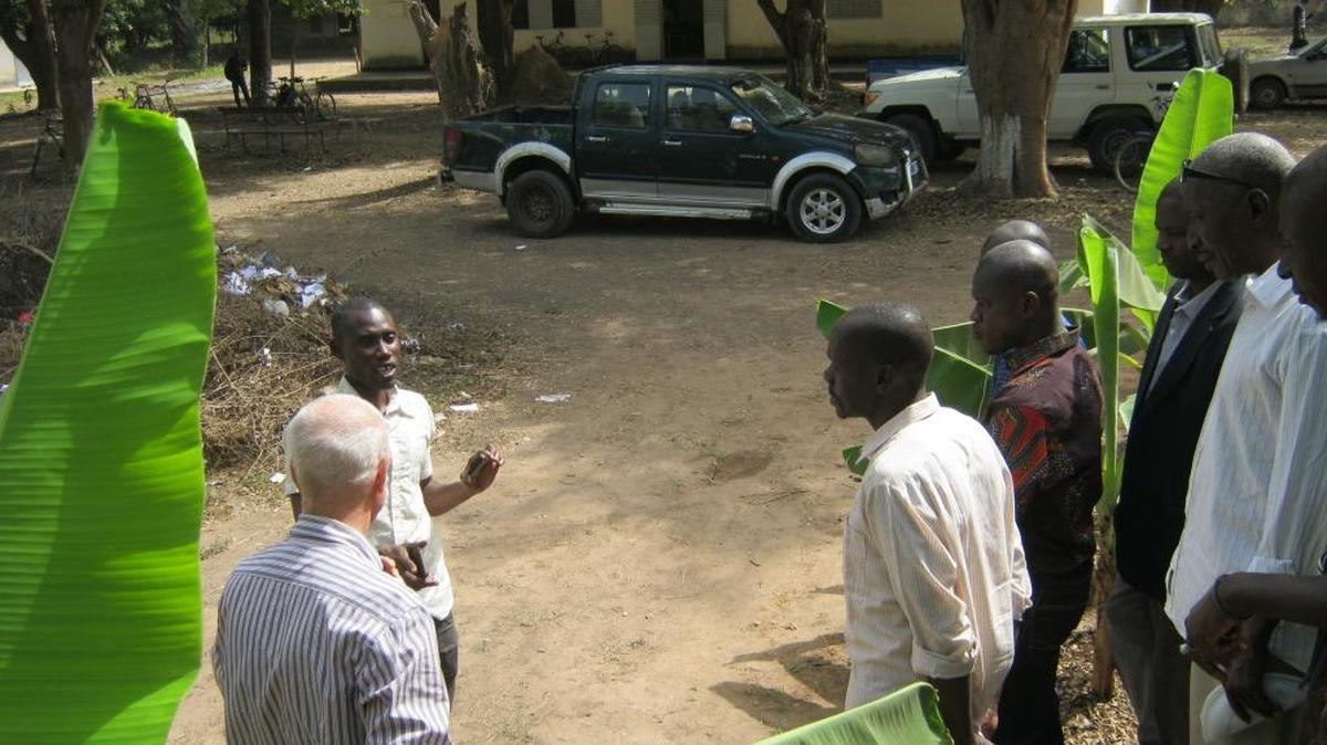 A group of Senegalese teachers gathers around an instructor from America, teaching about farming on a larger scale.