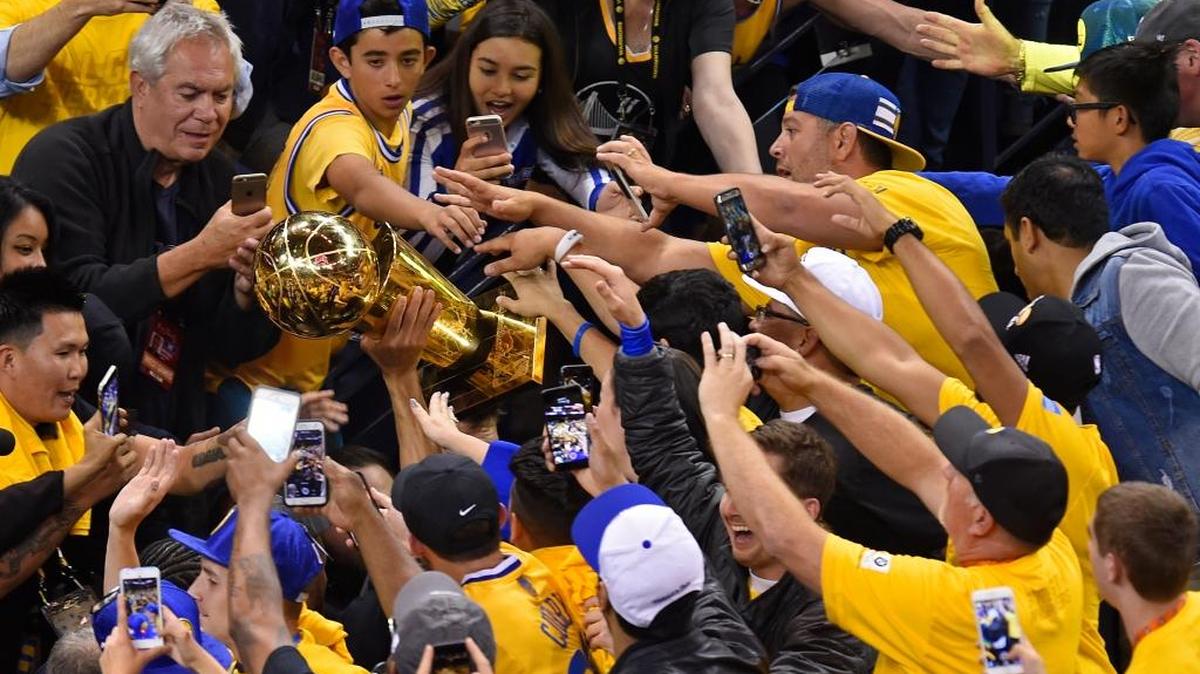 Fans rush the Warriors’ Stephen Curry as he walks through the tunnel holding the NBA championship trophy on Monday night. Nary a Lakers’ jersey could be found in Oracle Arena.