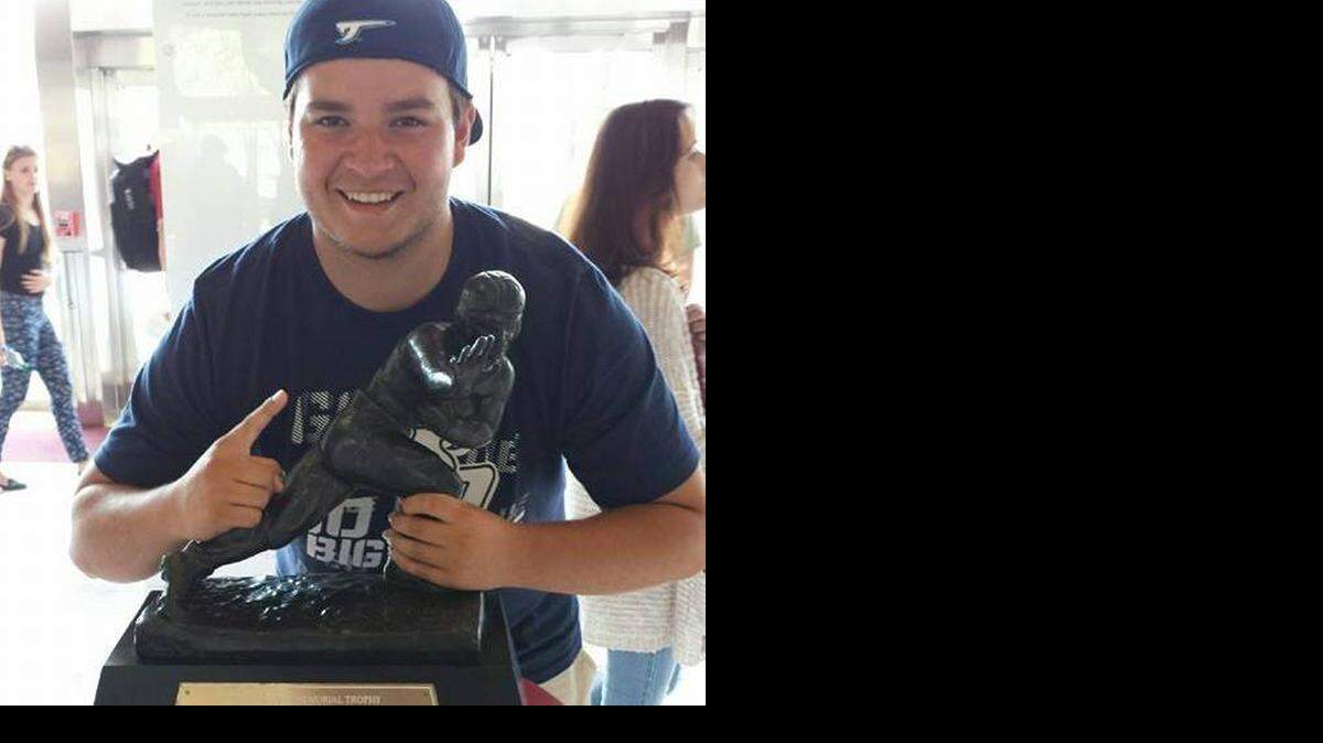 
High school football player Marty Wormuth poses with a replica of the Heisman Trophy. 
