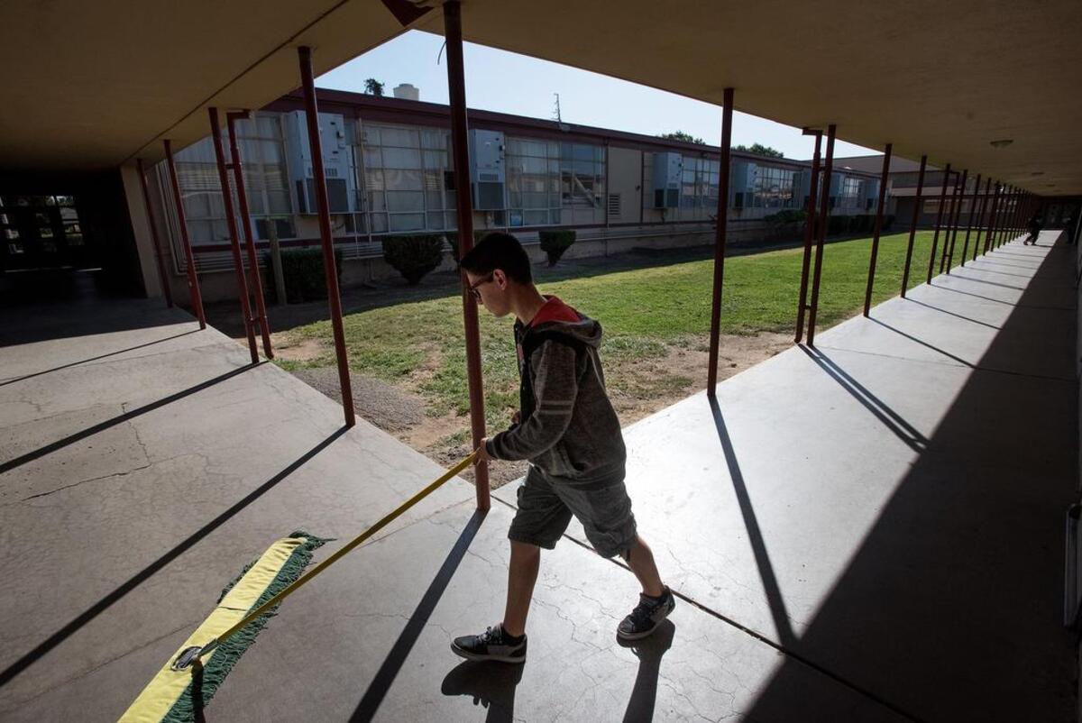 Mark Twain Junior High student John Paul Bellemane sweeps the walkway after school in 2018.