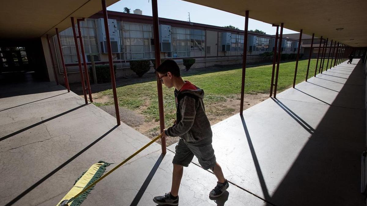 Mark Twain Junior High student John Paul Bellemane sweeps the walkway after school in 2018.