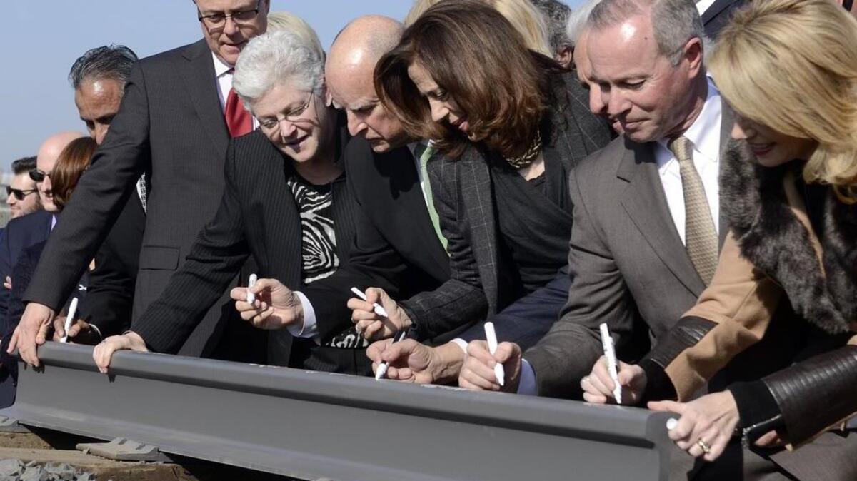 Then-Gov. Jerry Brown, center, ceremonously siged a section of rail, flanked by his wife, Anne Gust Brown, center right, and Gina McCarthy, former administrator for the EPA, center left, and other dignitaries sign at the groundbreaking for High Speed Rail in 2015. Others from left, Then Supervisor Henry Perea-partially seen, Joseph Szabo, administrator of the Federal Railroad Administration, Robbie Hunter, secretary-treasurer of the State Building and Construction Trades Council of California and former Fresno Mayor Ashley Swearengin.